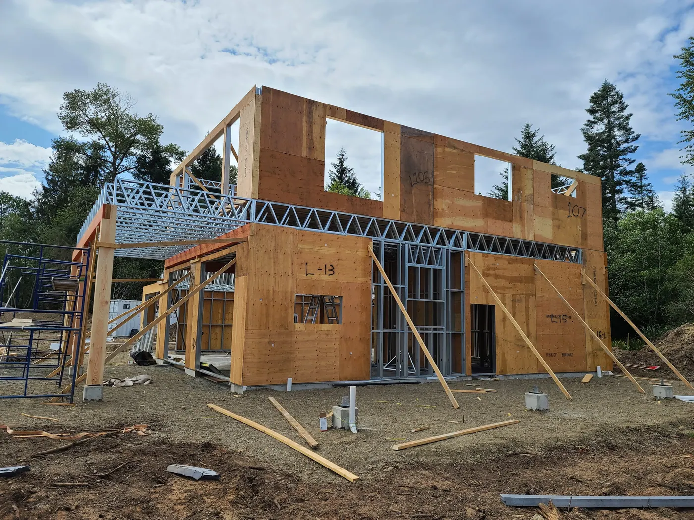 House under construction combining steel floor and roof framing with timber sheathing