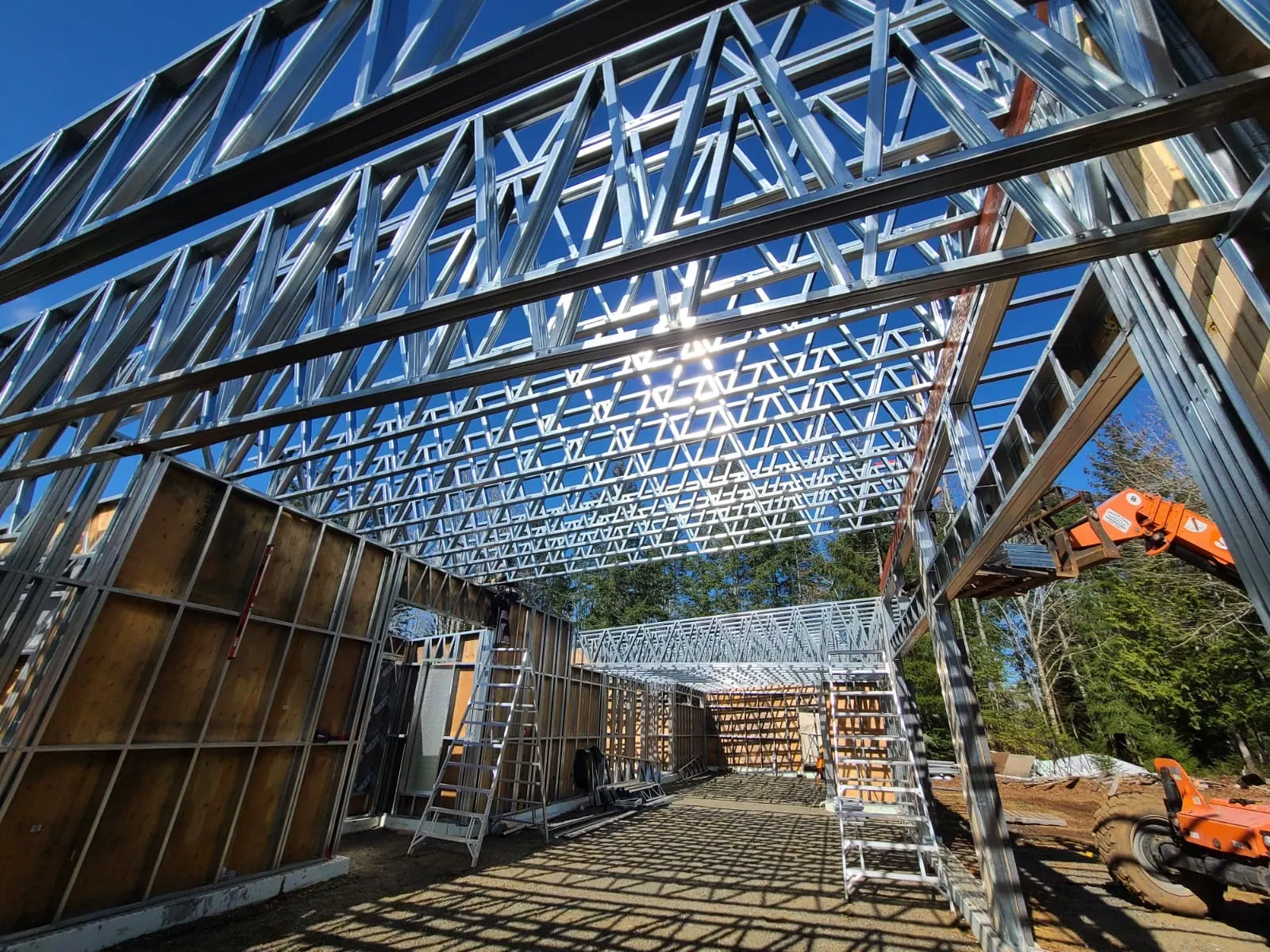 Crew installing light-gauge steel roof trusses over steel-framed walls