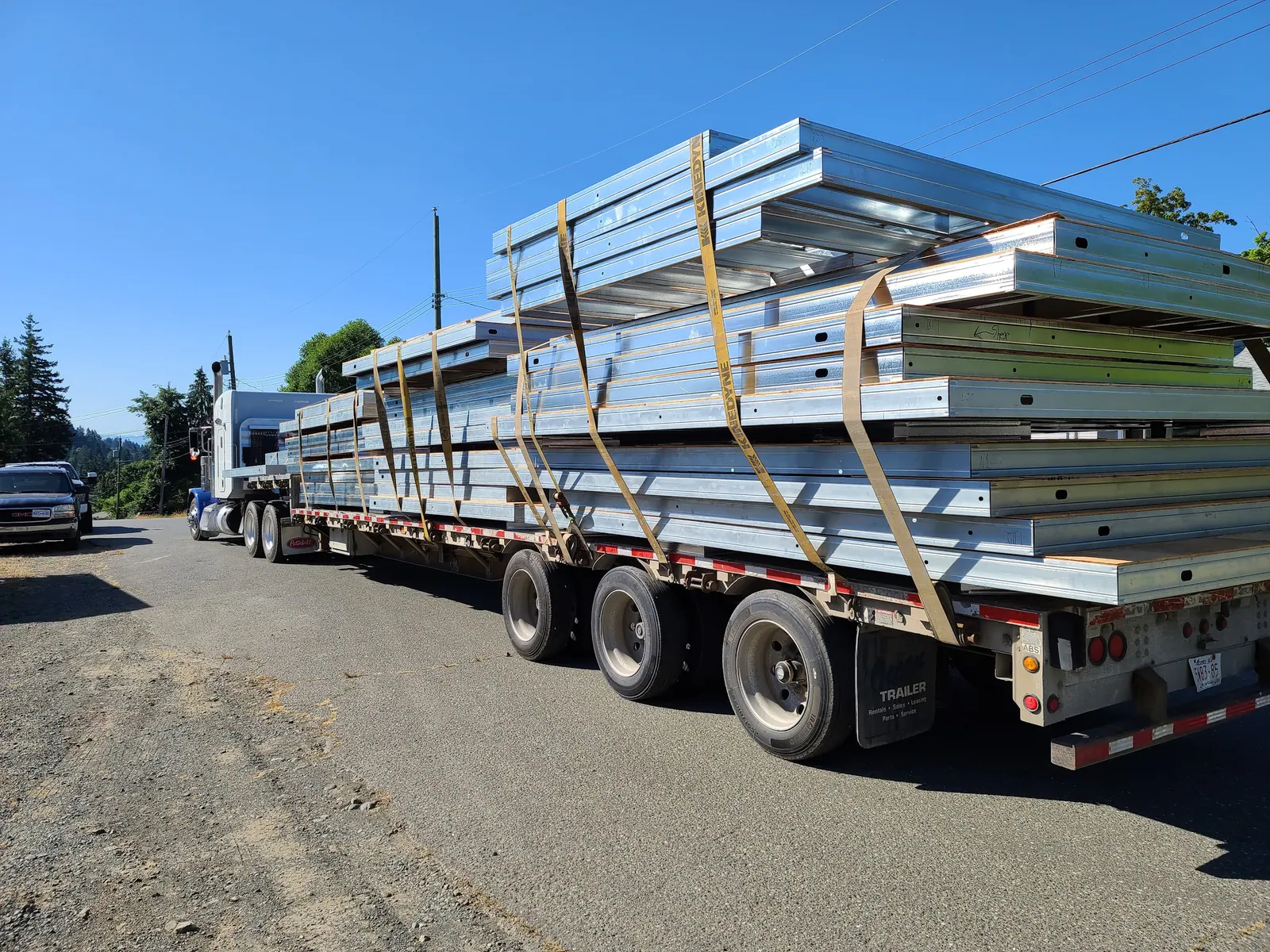Flatbed truck loaded with bundled steel framing and trusses
