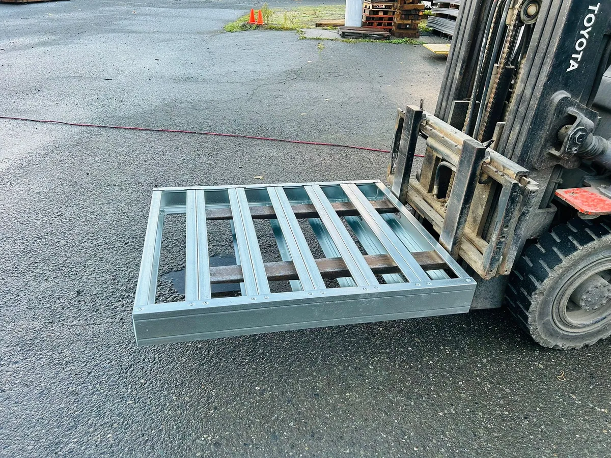 Galvanized closed-deck steel pallet lifted on forklift forks